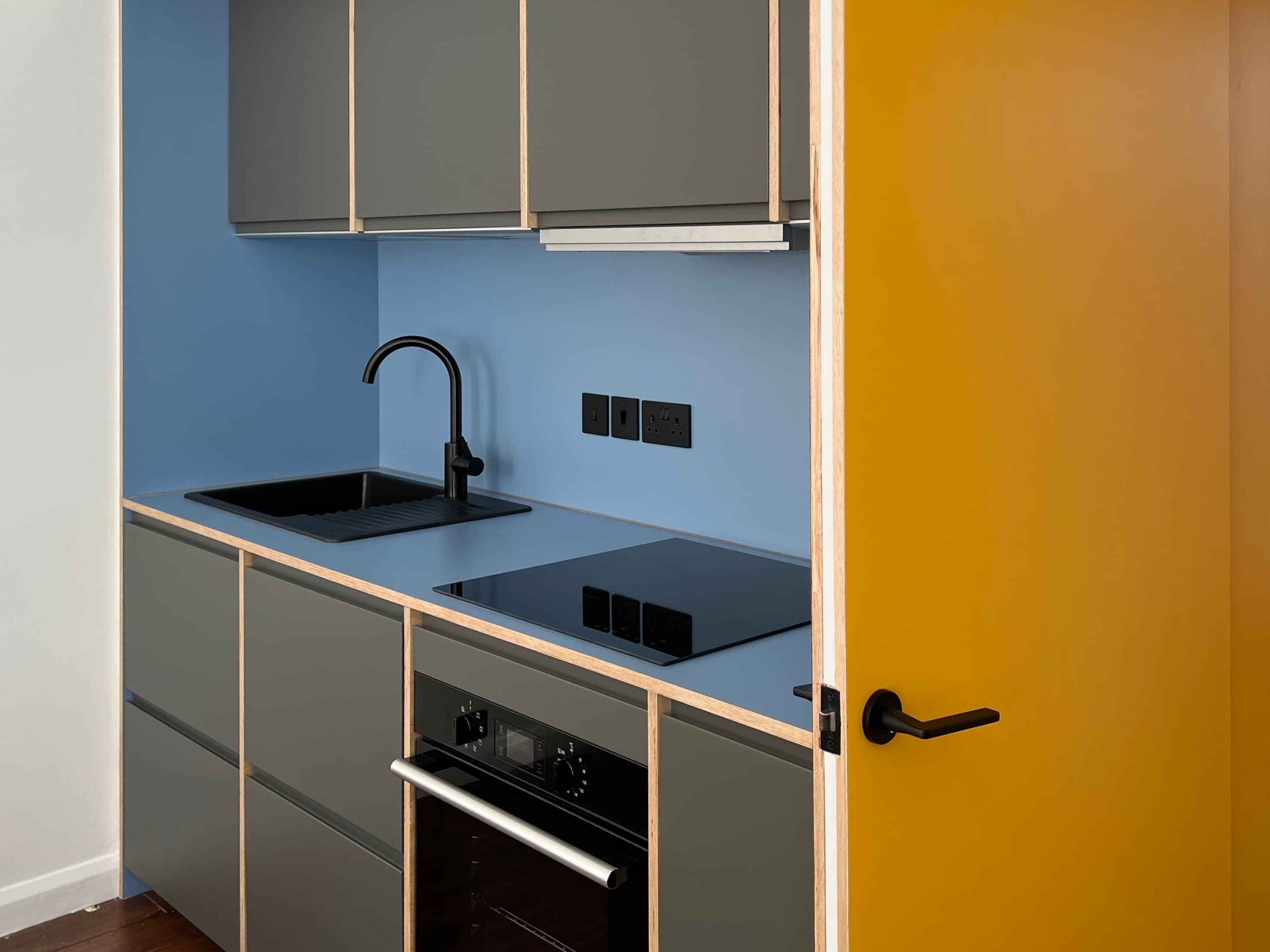 Kitchen worktop, hob, sink and yellow door detail
